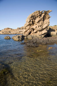 Rock formation on beach against clear sky