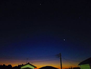 Low angle view of silhouette electricity pylon against sky at night