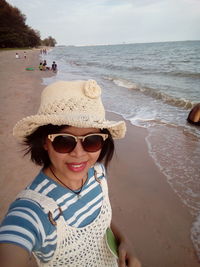 Portrait of smiling young woman in sunglasses at beach