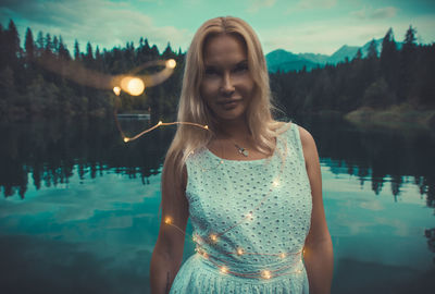 Portrait of woman standing by lake with illuminated lighting equipment