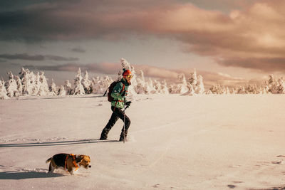 Rear view of girl with dog on snow