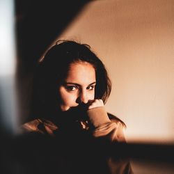 Portrait of young woman against wall at home