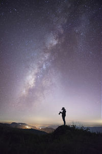 Silhouette man standing on field against sky at night