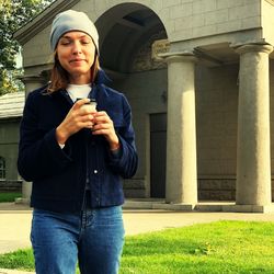 Portrait of woman having drink while standing against building