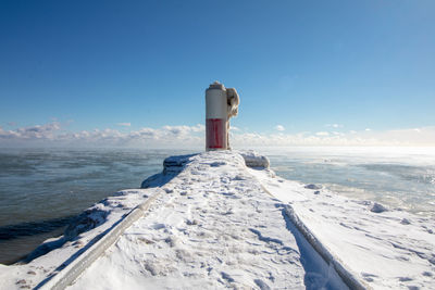 Scenic view of sea and snowcapped mountains against blue sky