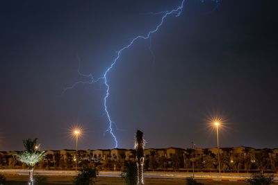 Low angle view of lightning over illuminated city at night
