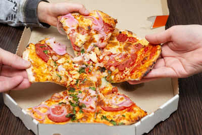 Cropped hand holding pizza on table