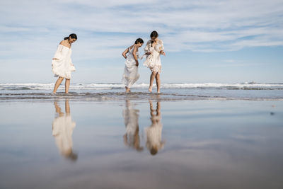 People on beach by sea against sky