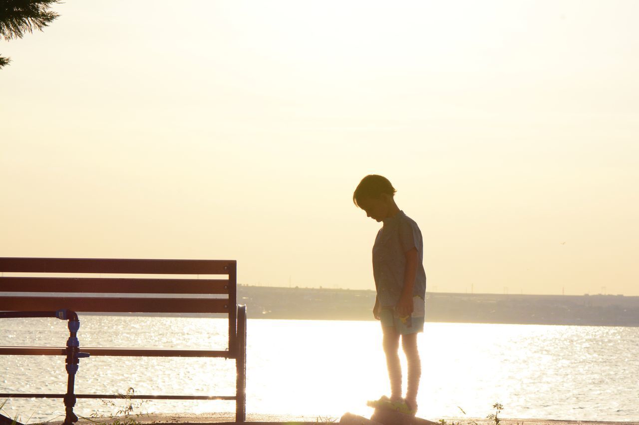 MAN STANDING ON SEA AGAINST SKY