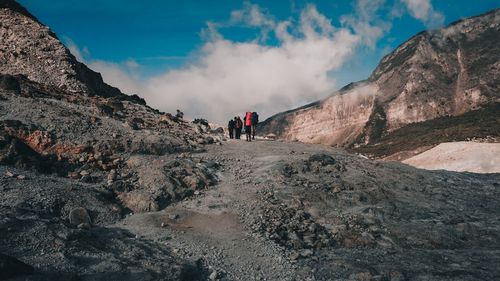 Rear view of people on rock against sky