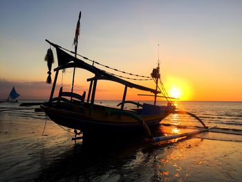 Silhouette boats moored on sea against sky during sunset