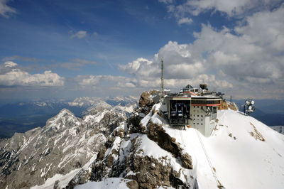 Communication tower on mountain peak against cloudy sky