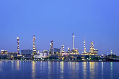 Illuminated factory against blue sky at night