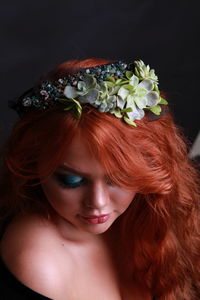 High angle close-up of sensuous young woman wearing wreath against black background