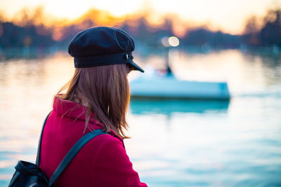 Rear view of woman looking at lake during sunset