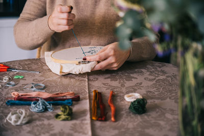 Midsection of man holding plastic arranged on table