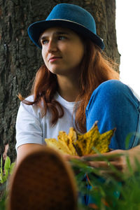 Portrait of a dreamy young woman with brown hair wearing a hat outdoors in autumn, fall