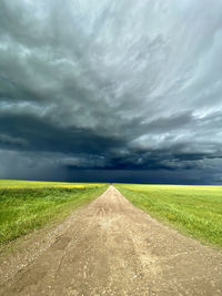 Road amidst field against sky