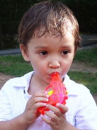 Cute boy sucking toy handgun outdoors