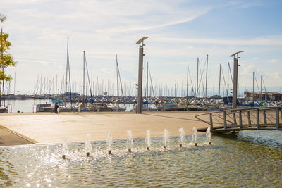 Sailboats moored at harbor against sky