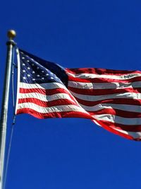 Low angle view of american flag against clear blue sky