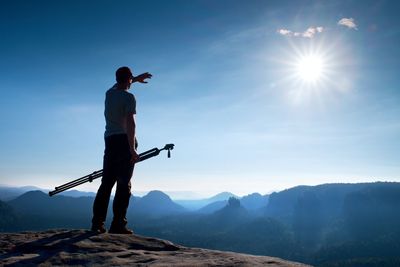 Professional photographer with tripod on cliff and think. dreamy misty sunrise in beautiful valley