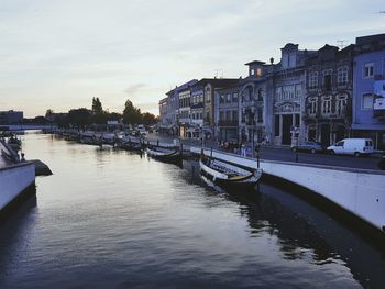 Boats moored at harbor against sky in city