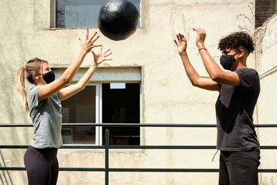 Couple wearing mask exercising with ball outdoors