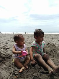 Siblings sitting on beach