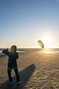 Woman kiteboarding at beach against clear sky