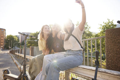 Young female friends spending time together outdoors and taking selfie