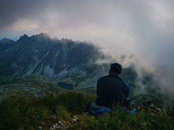 Rear view of man standing on mountain against sky