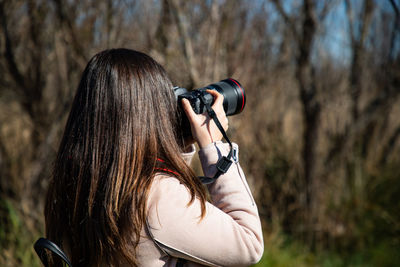 Rear view of woman photographing with camera