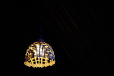 Low angle view of illuminated lamp against black background