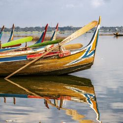 Fishing boats moored in lake against sky