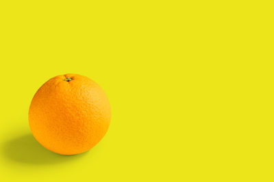 Close-up of orange fruit against yellow background