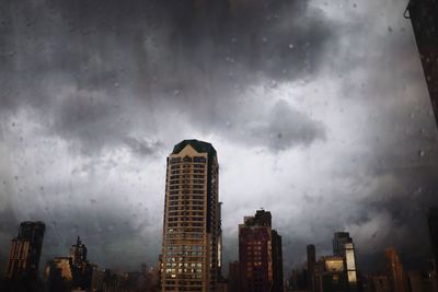Modern buildings in city against storm clouds
