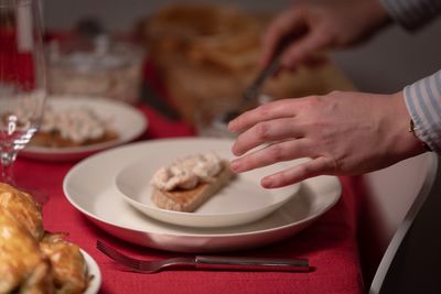 Midsection of woman preparing food in plate on table