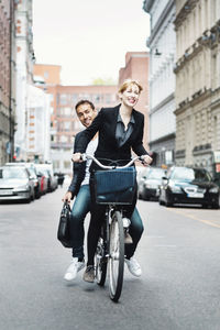 Happy business people riding bicycle on city street