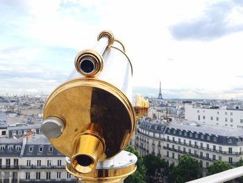 Close-up of coin-operated binoculars against buildings in city