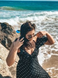 Young woman wearing sunglasses while standing on beach