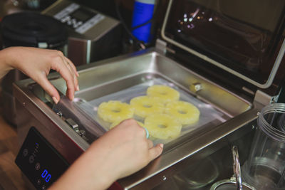 Cropped hands preparing food in appliance at kitchen