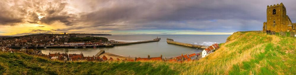 Panoramic view of sea and buildings against sky during sunset