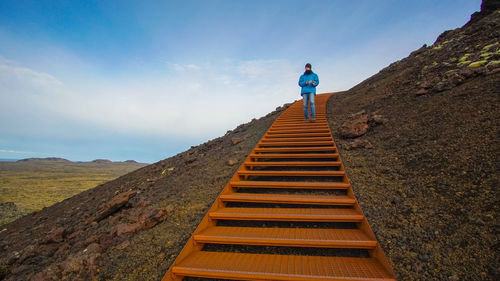 Rear view of man standing on staircase against sky