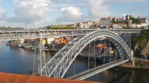 Bridge over river in city against sky