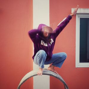 Portrait of young woman exercising against wall 