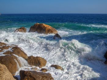 Scenic view of rocks in sea against sky