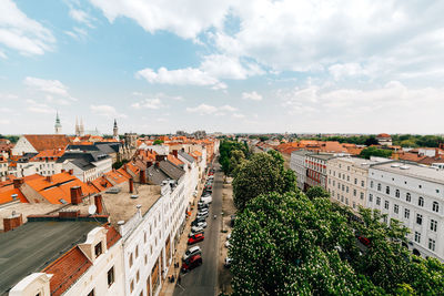 Trees amidst buildings in town against sky