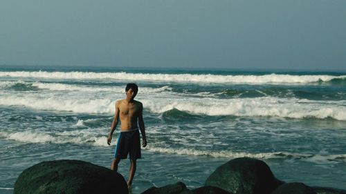 Rear view of shirtless man looking at sea