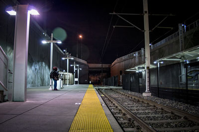 People standing on railroad station platform at night
